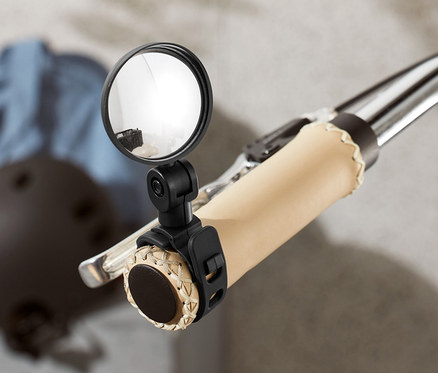 Detail kola se zrcátkem na řídítkách. V pozadí je helma a bunda.