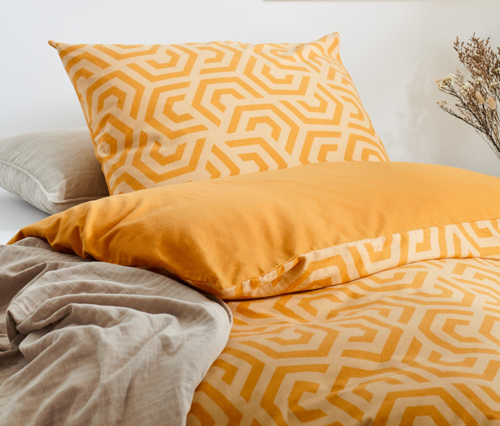 Žluté povlečení s geometrickým vzorem a prostěradlo.