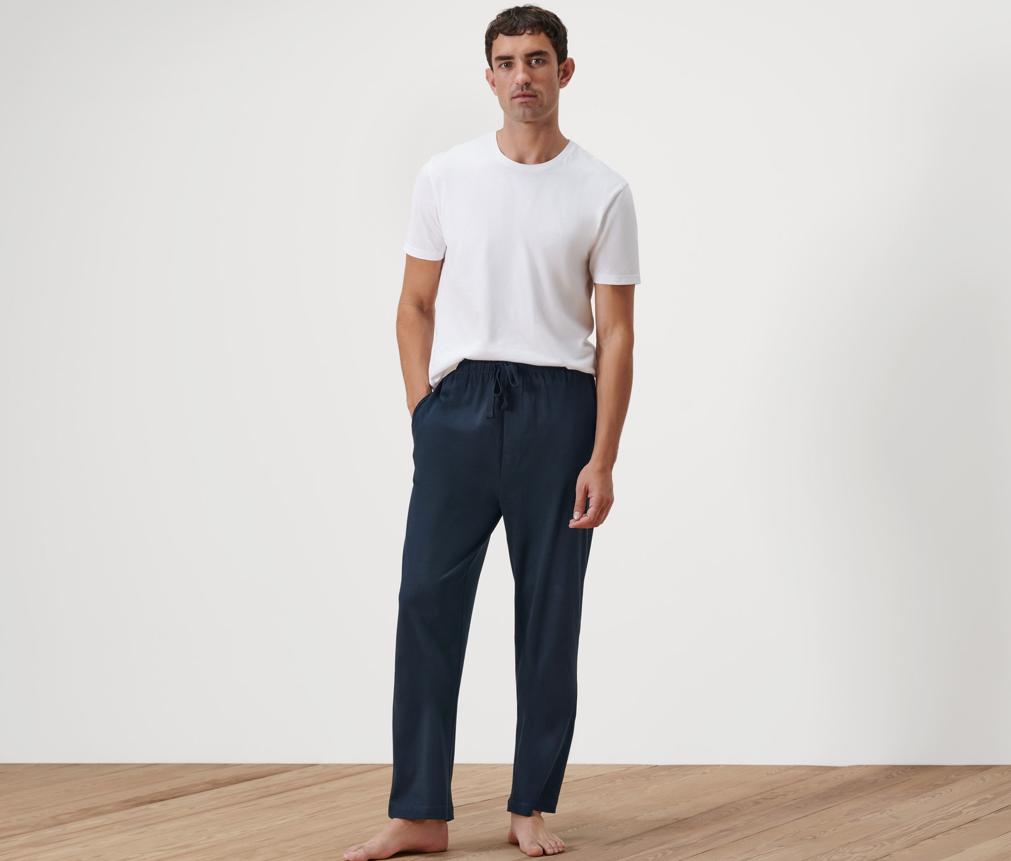 Muž stojí a má ruce v kapsách pohodlných kalhot.