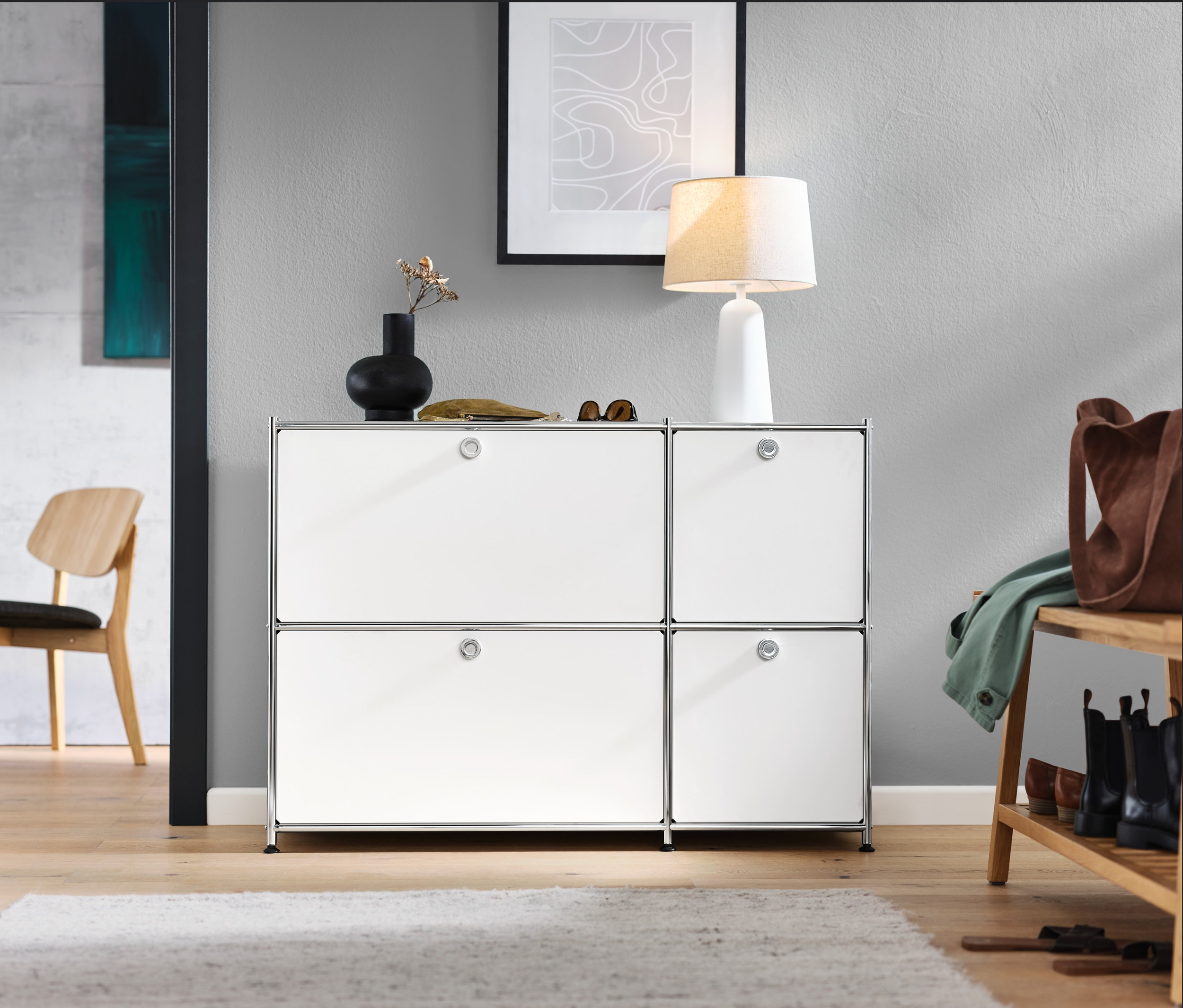 Vstupní hala s bílou odkládací skříňkou CN3 se 4 výklopnými dvířky, lounge židlí, lavicí na sezení s odkládací plochou a bílou stolní lampou s textilním stínidlem.