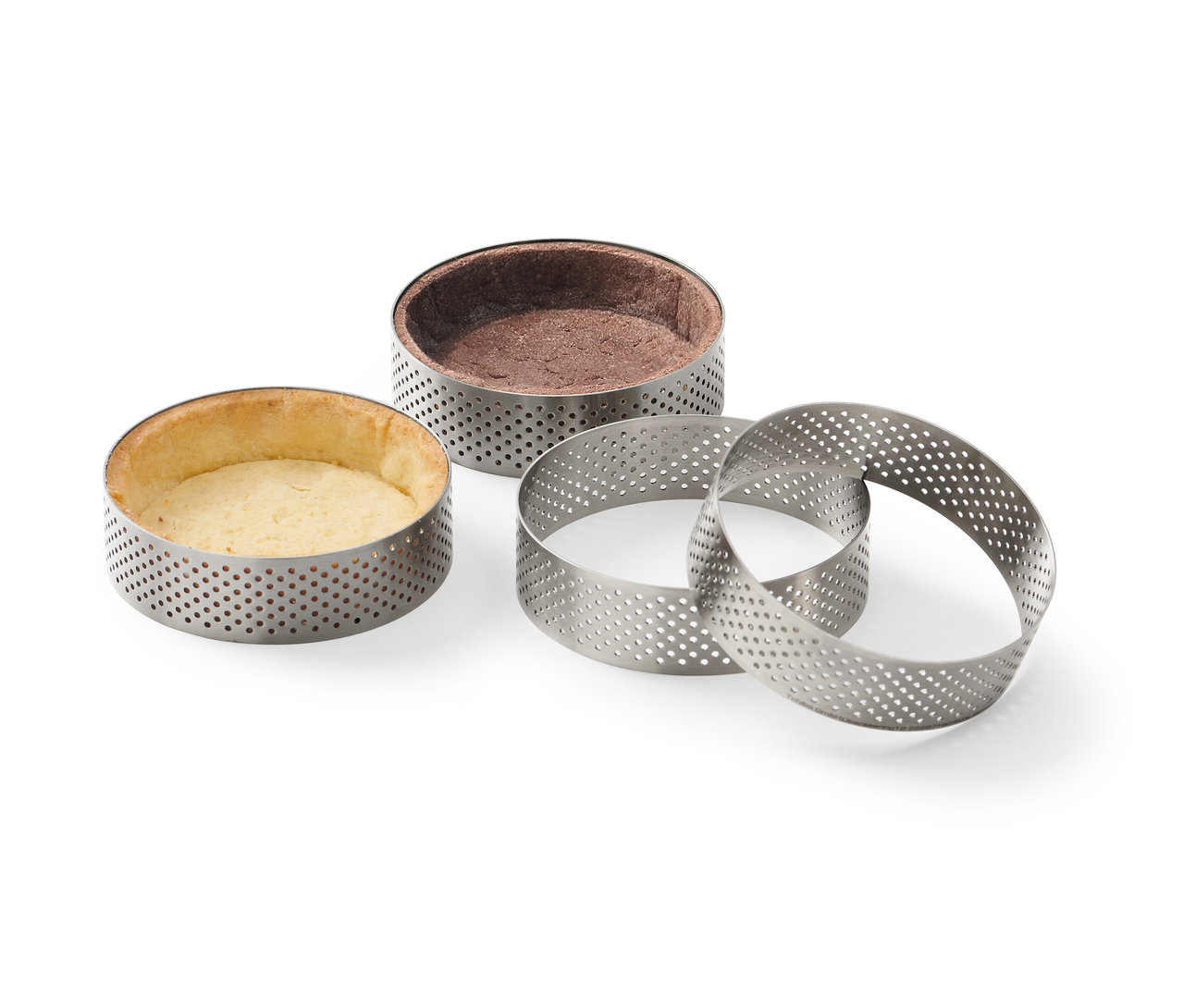 Čtyři nerezové pečicí ráfky, dva s upečeným těstem.