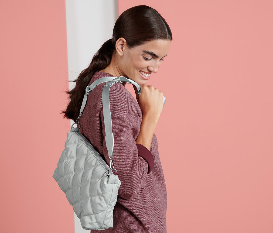 Žena se usmívá a má přes rameno kabelku.