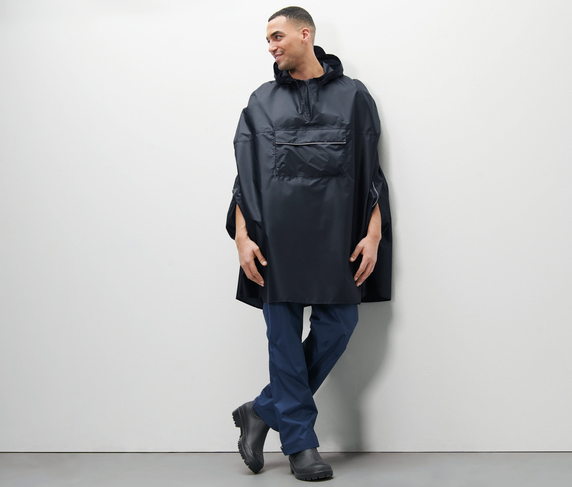 Muž pózuje v modrém unisex ponču do deště.
