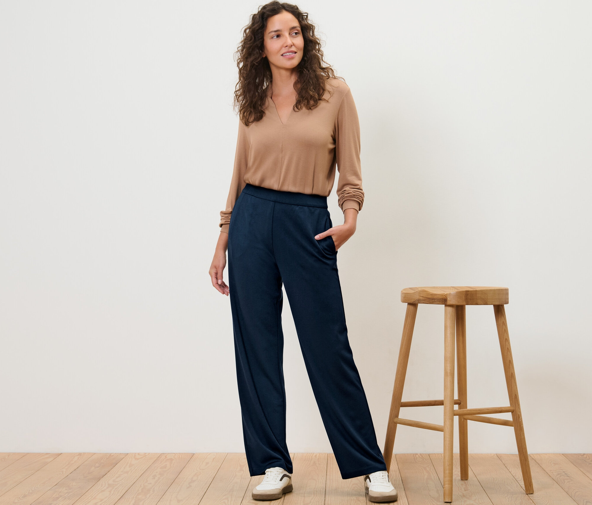 Žena stojí a pózuje v pohodlných žerzejových kalhotách.