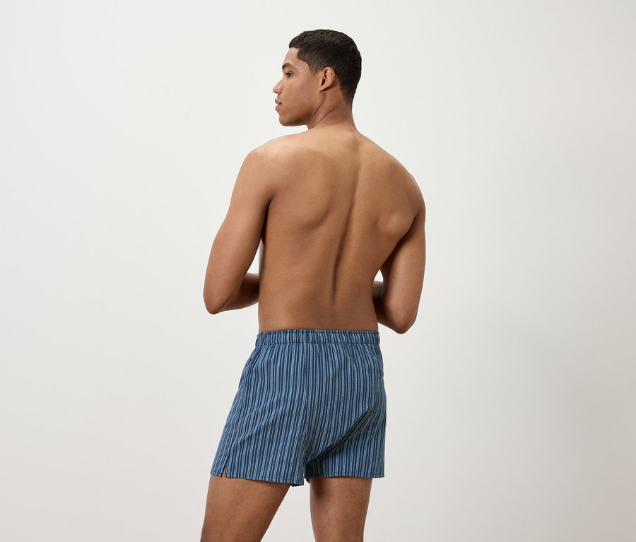 Muž zády ke kameře má na sobě modré pruhované trenýrky.