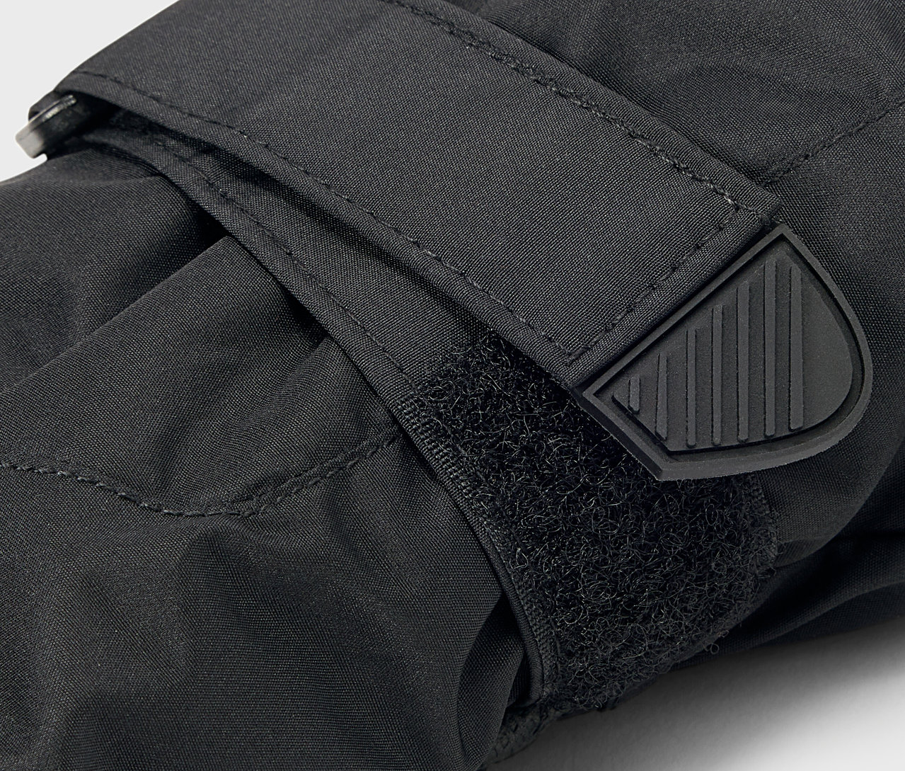 Detail černé rukavice se zapínáním na suchý zip a gumovým zakončením pásku.