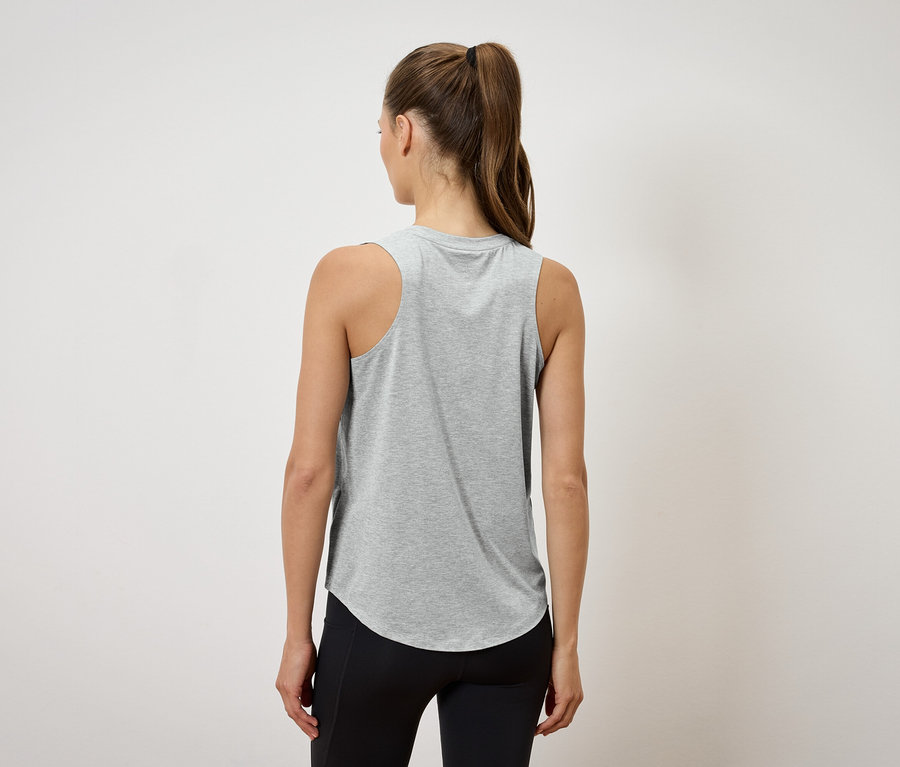 Zezadu je vidět žena s culíkem, která má na sobě šedé tílko a černé legíny.