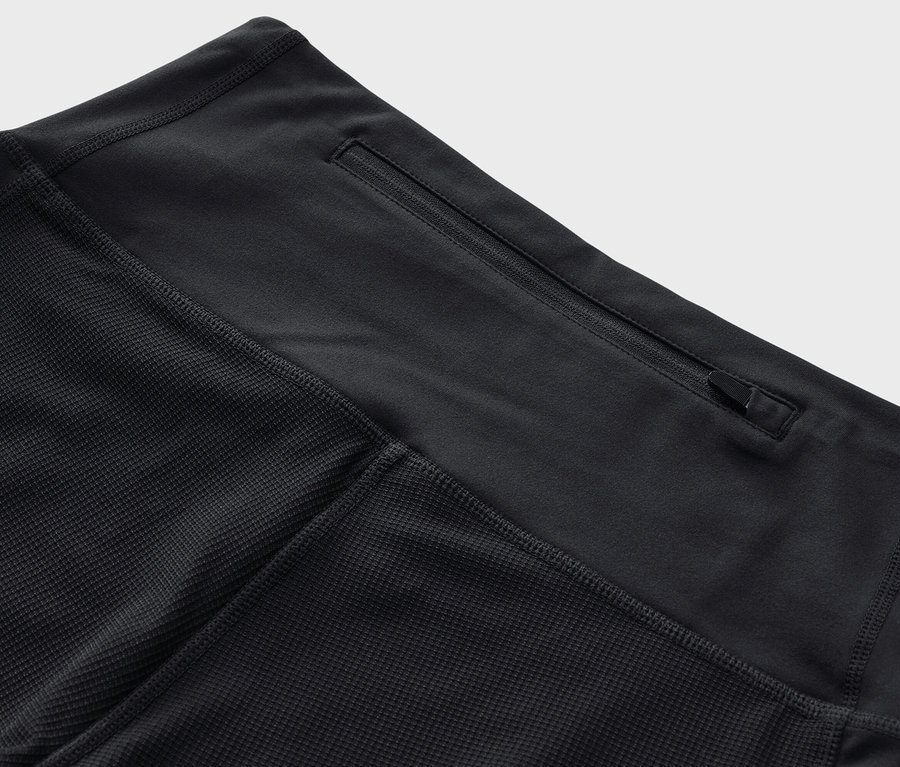 Detailní záběr na černé 3/4 trekingové legíny se zipovou kapsou v pase.