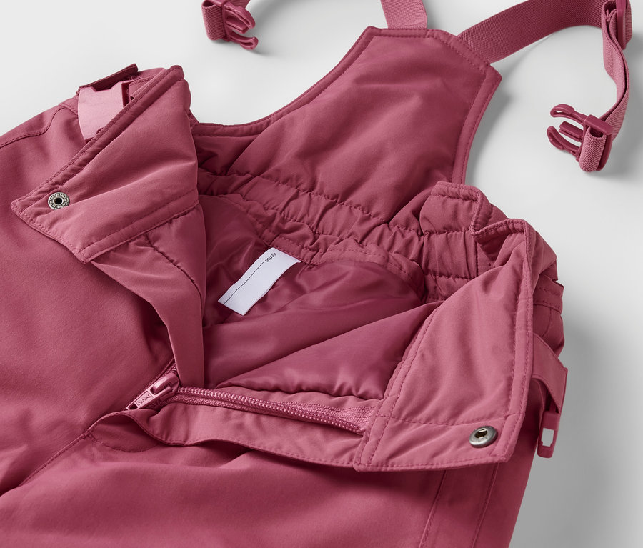 Detailní záběr na rozepnutou dětskou zimní kombinézu 2dílné soupravy v růžové barvě.