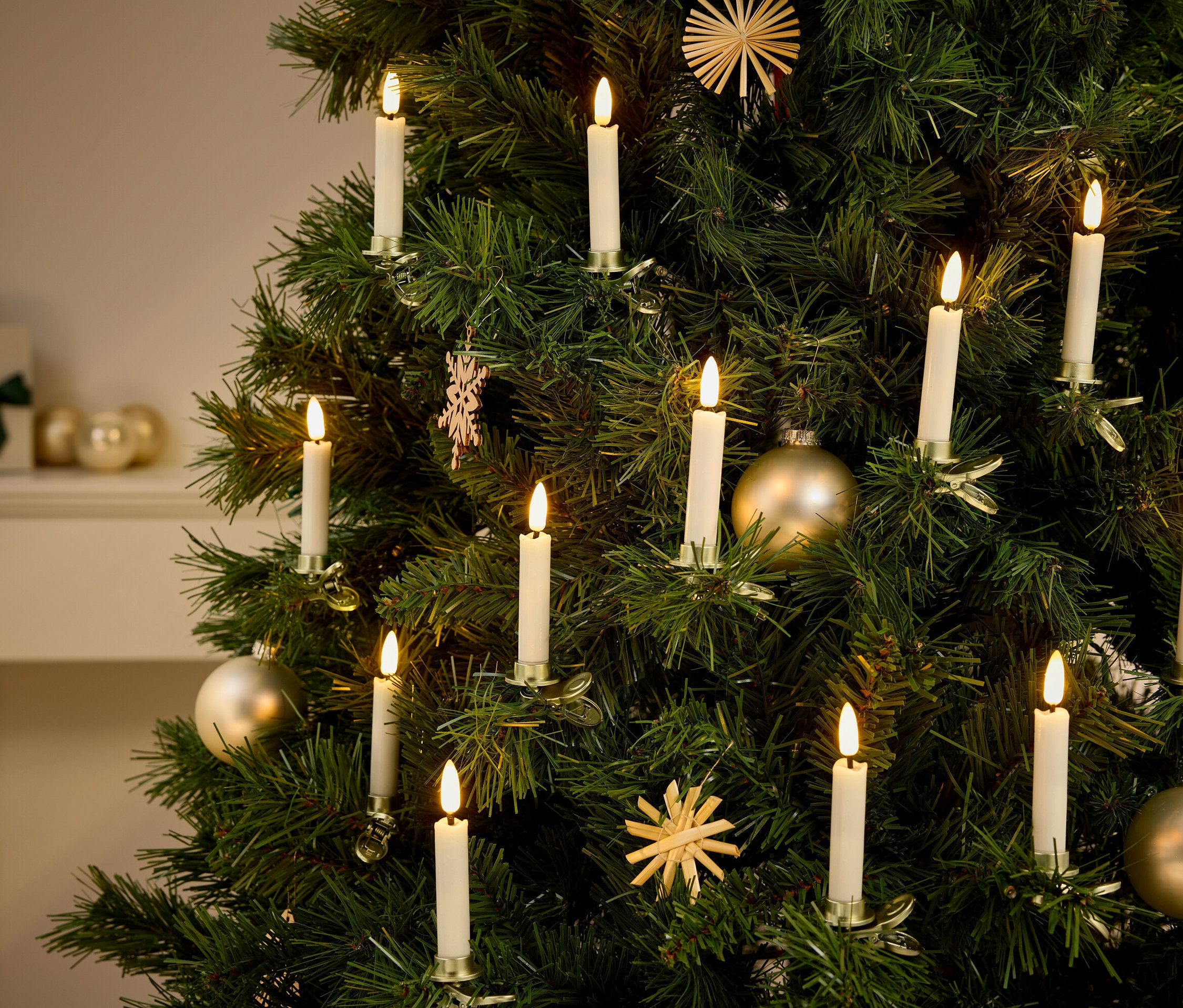 Detail vánočního stromku s ozdobami a světly ve tvaru svíček.