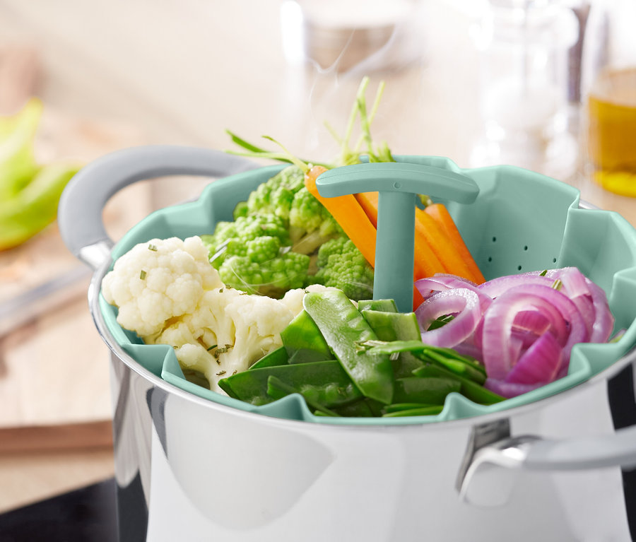 Zelenina v napařovacím sítu nad hrncem.