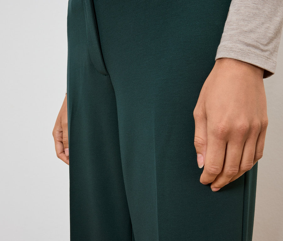 Detail dámských kalhot tmavě zelené barvy.