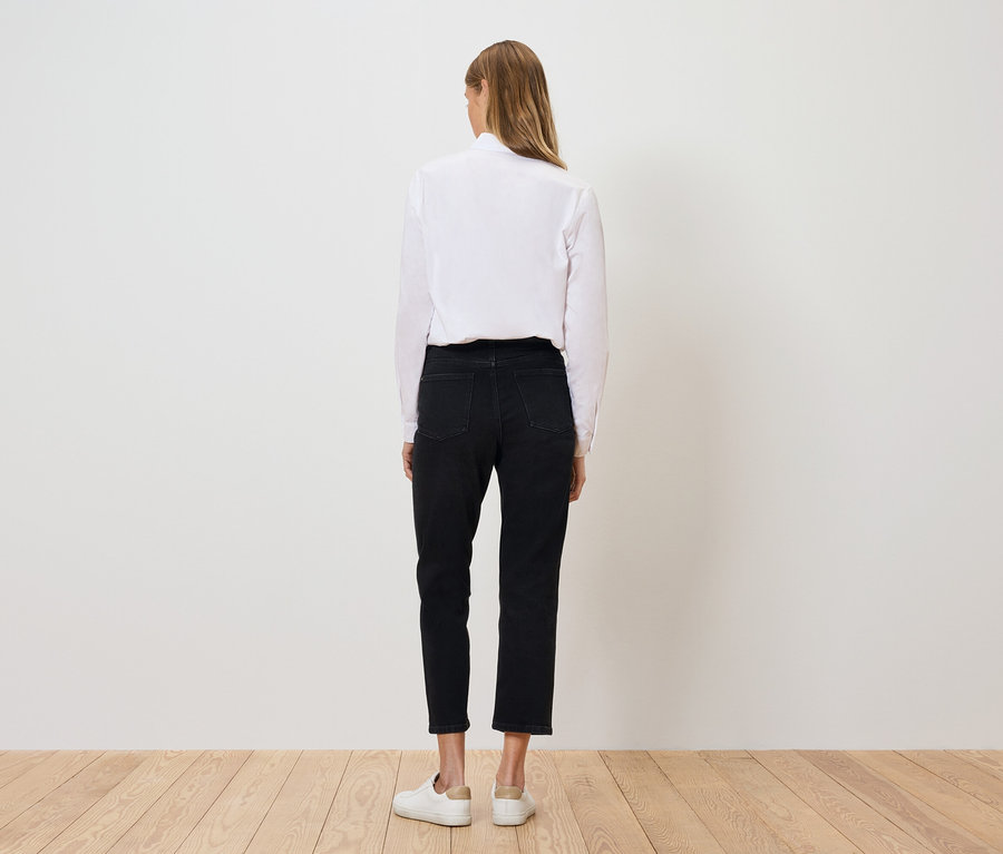 Zezadu je vidět žena v bílé košili, černých kalhotách a bílých botách.