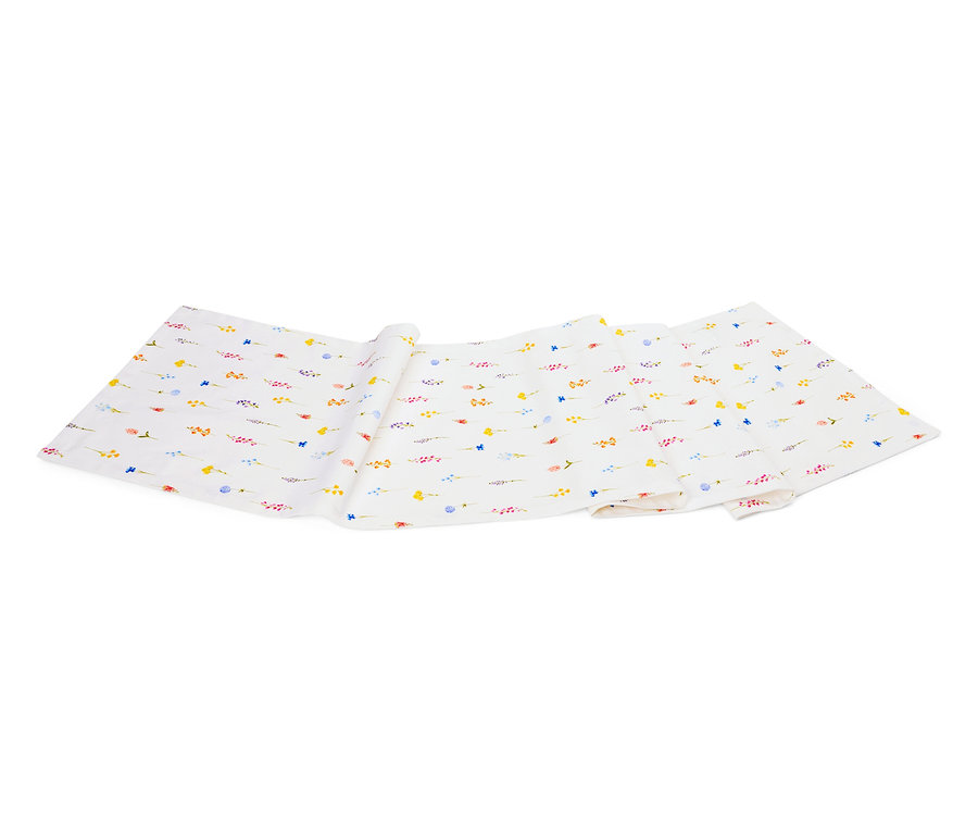 Bílá látka se vzorem malých barevných květin leží složená na bílém pozadí.