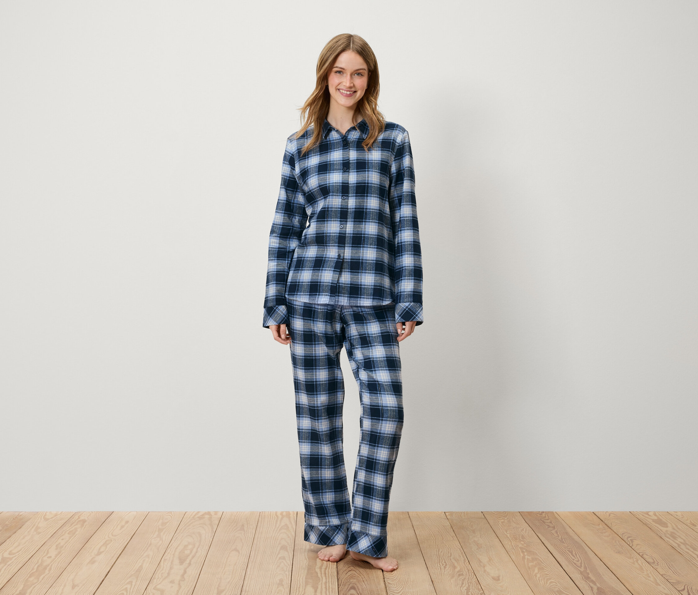 Žena stojí a má na sobě modré kostkované pyžamo.