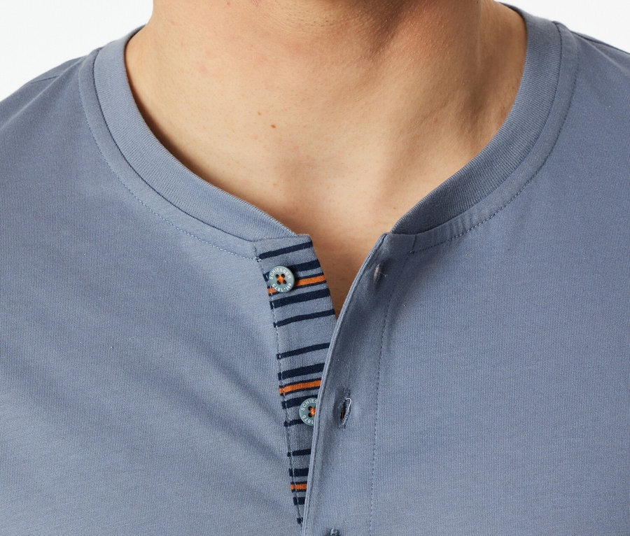 Detail muže v modrém polo tričku s knoflíky a pruhovaným detailem.