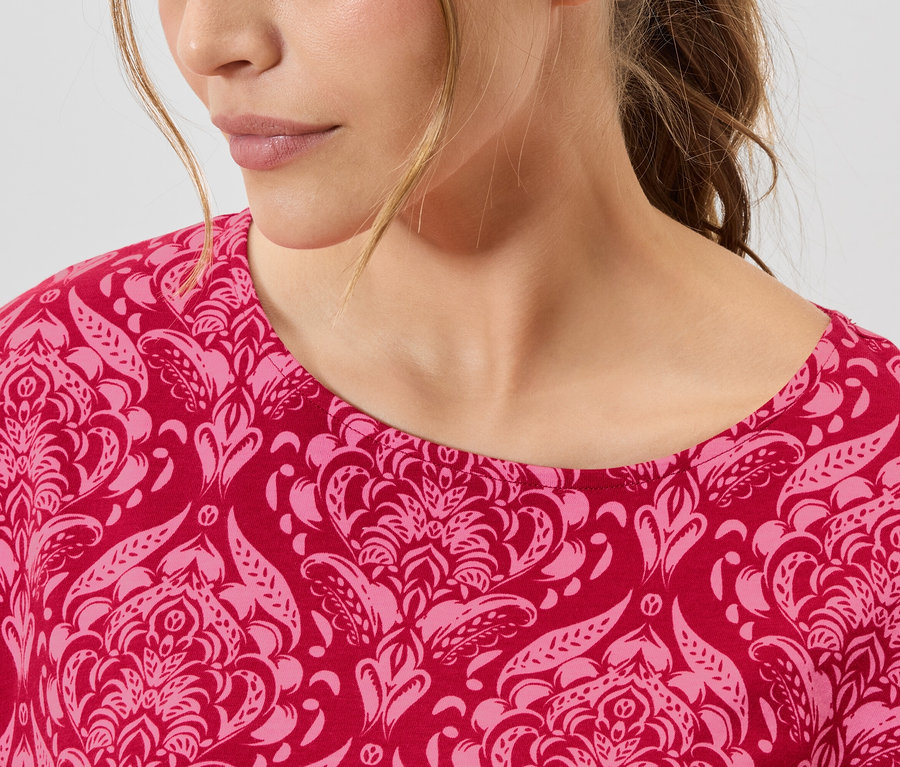 Detailní záběr ženy v červeno-růžovém vzorovaném topu.