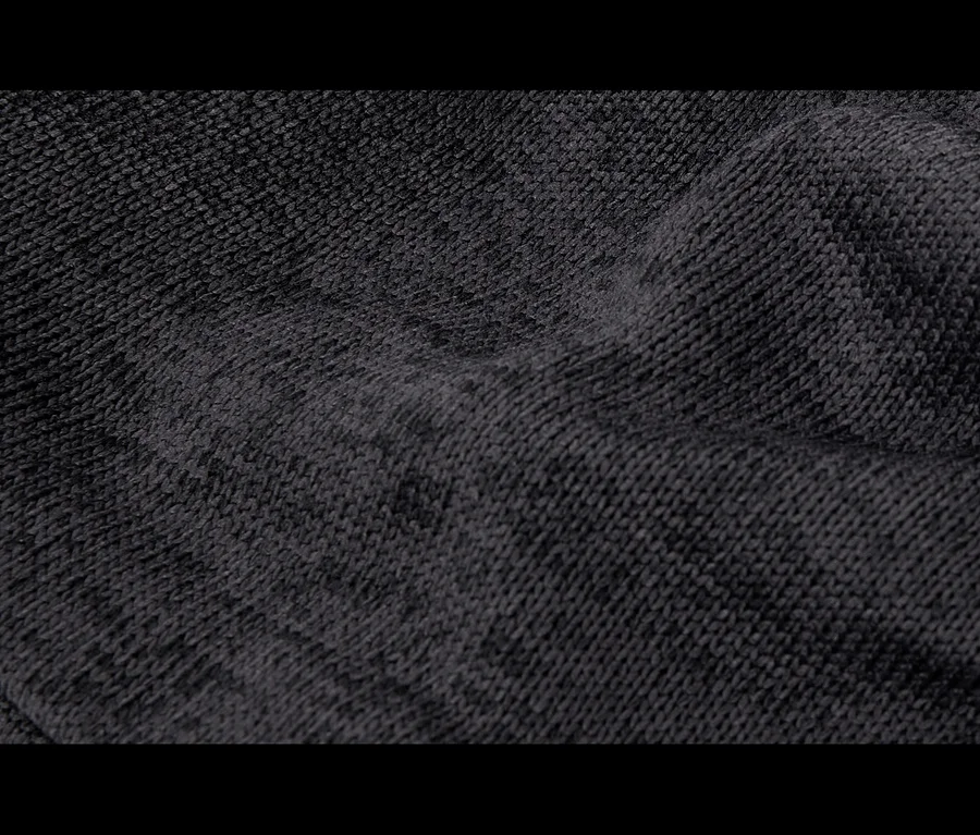 Detail tmavě šedé, měkké pletené látky s záhyby a lehce chmýřovitou texturou.