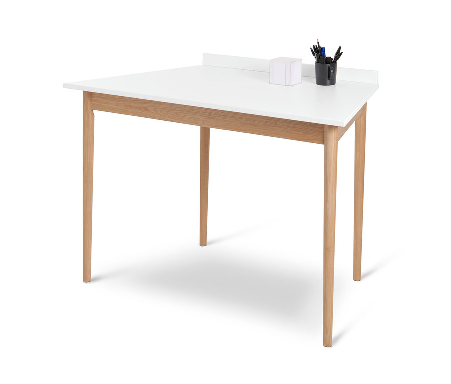 Bílý trapézový stůl se čtyřmi dřevěnýma nohama a černým hrnkem s psacími potřebami.