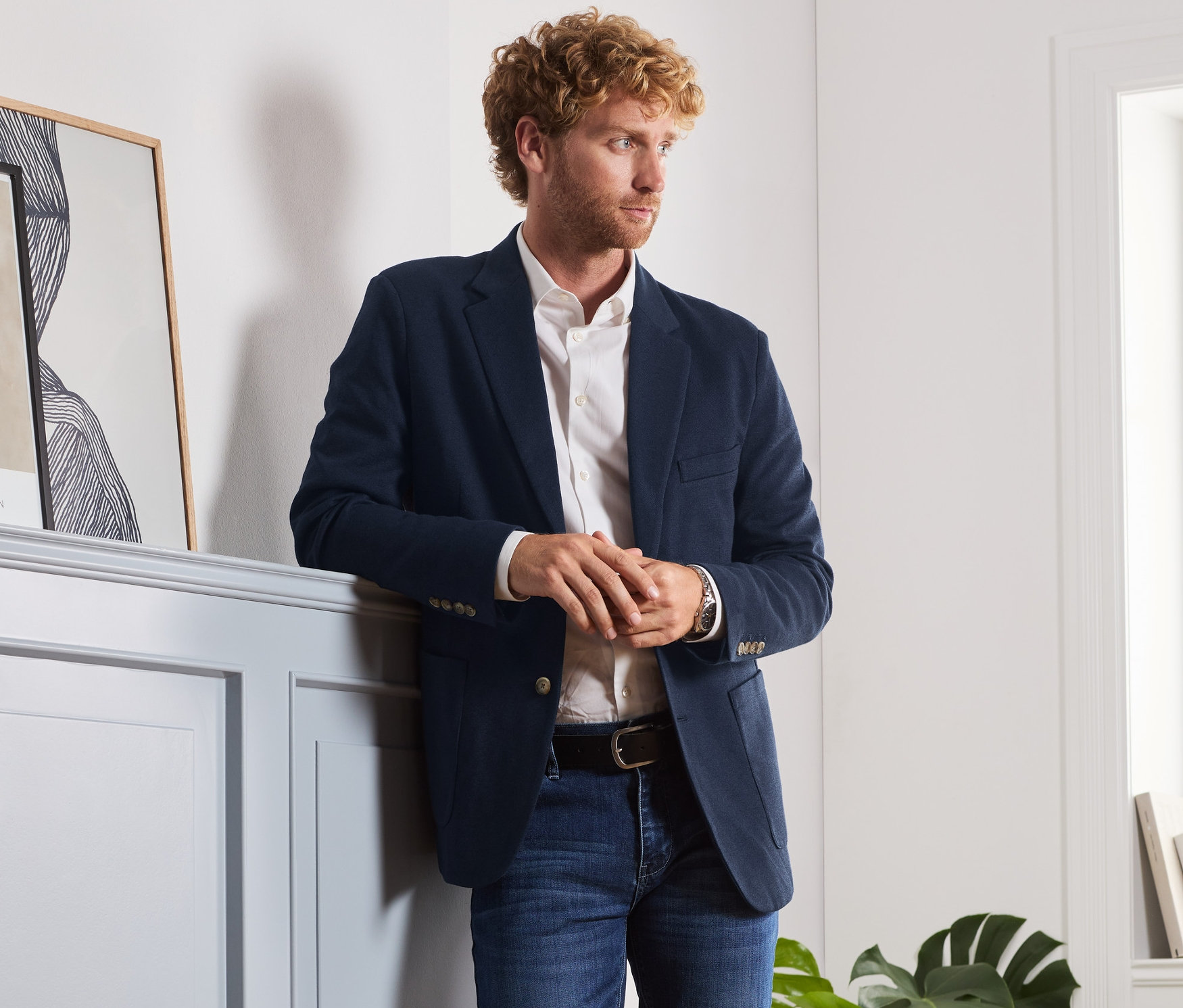 Muž opřený o zeď má na sobě sako.