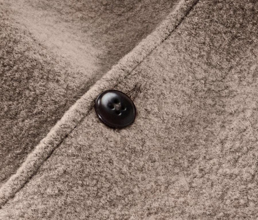 Detail hnědé kombinézy pro kojence s vlnou merino a knoflíkem.