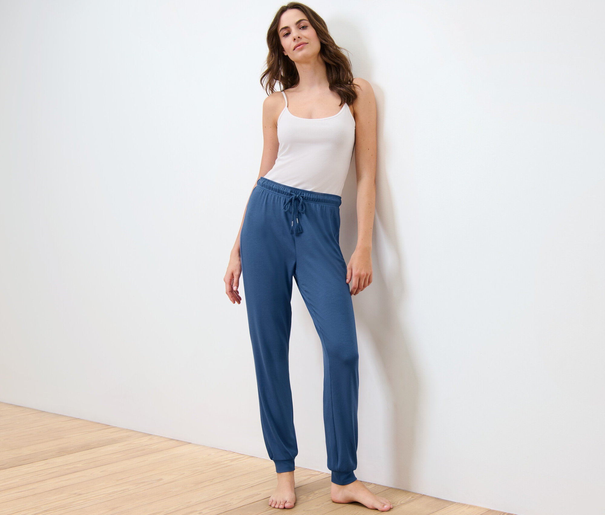 Žena pózuje v pyžamových kalhotách a tílku.