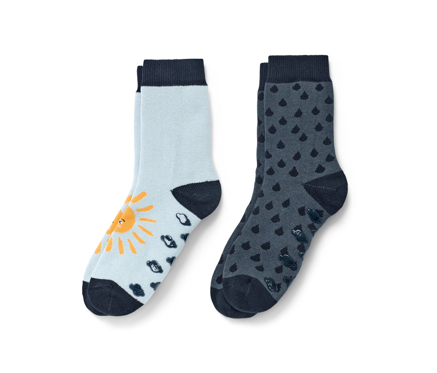 Dvoje dětské protiskluzové ponožky modré barvy. Jedny světle modré se žlutým sluncem a tmavě modrými mráčky, druhé tmavě modré s kapkami.