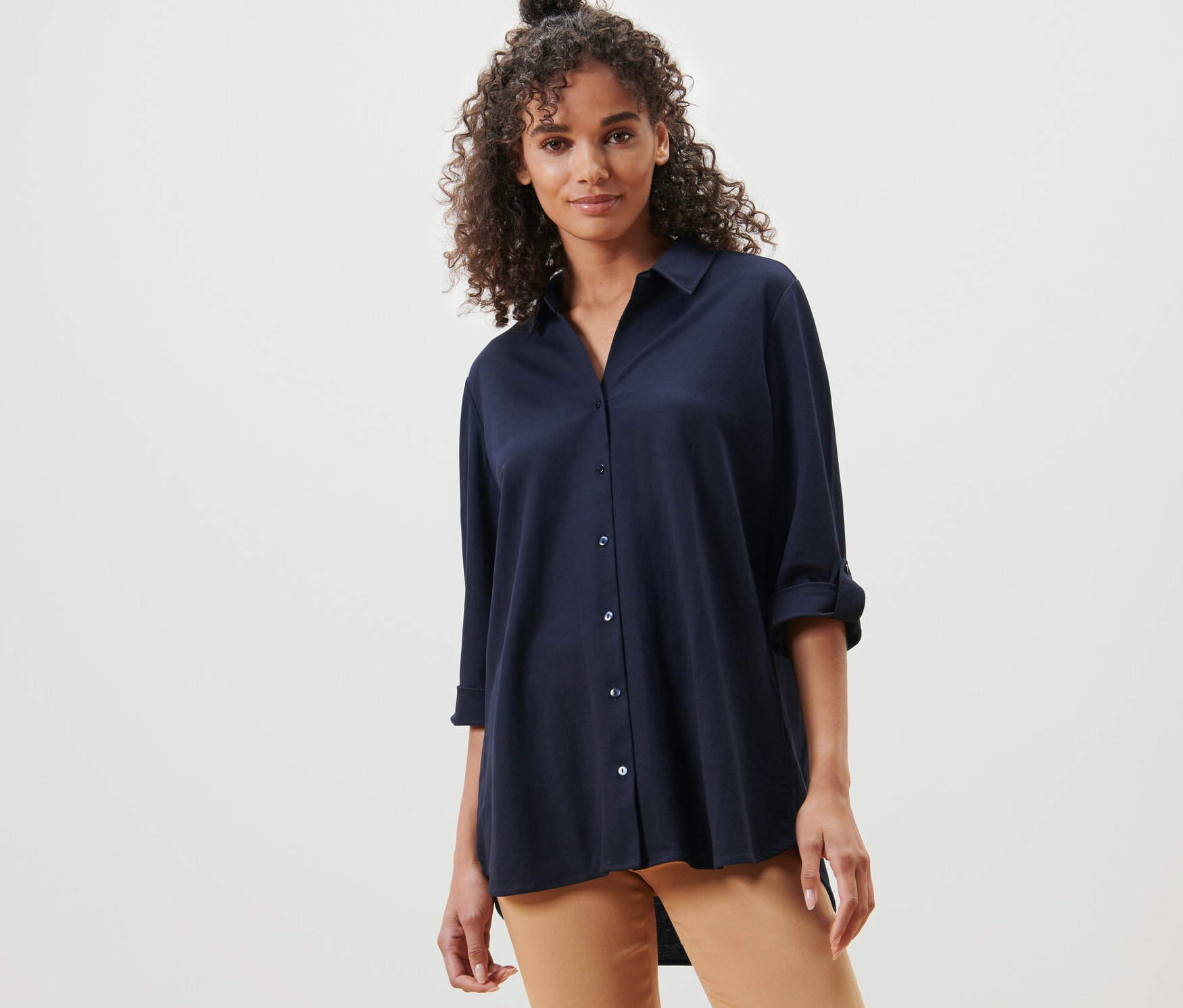 Žena pózuje v tmavě modré halence z žerzejového piké.