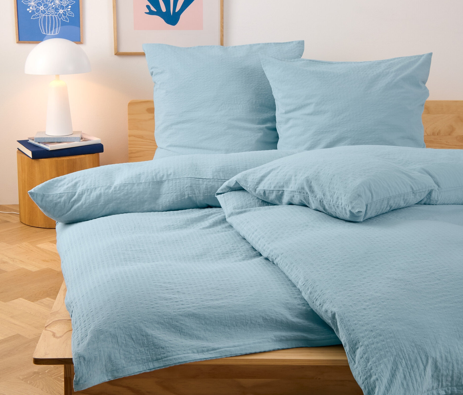 Světle modré krepové povlečení standardní a nadměrné velikosti na posteli.