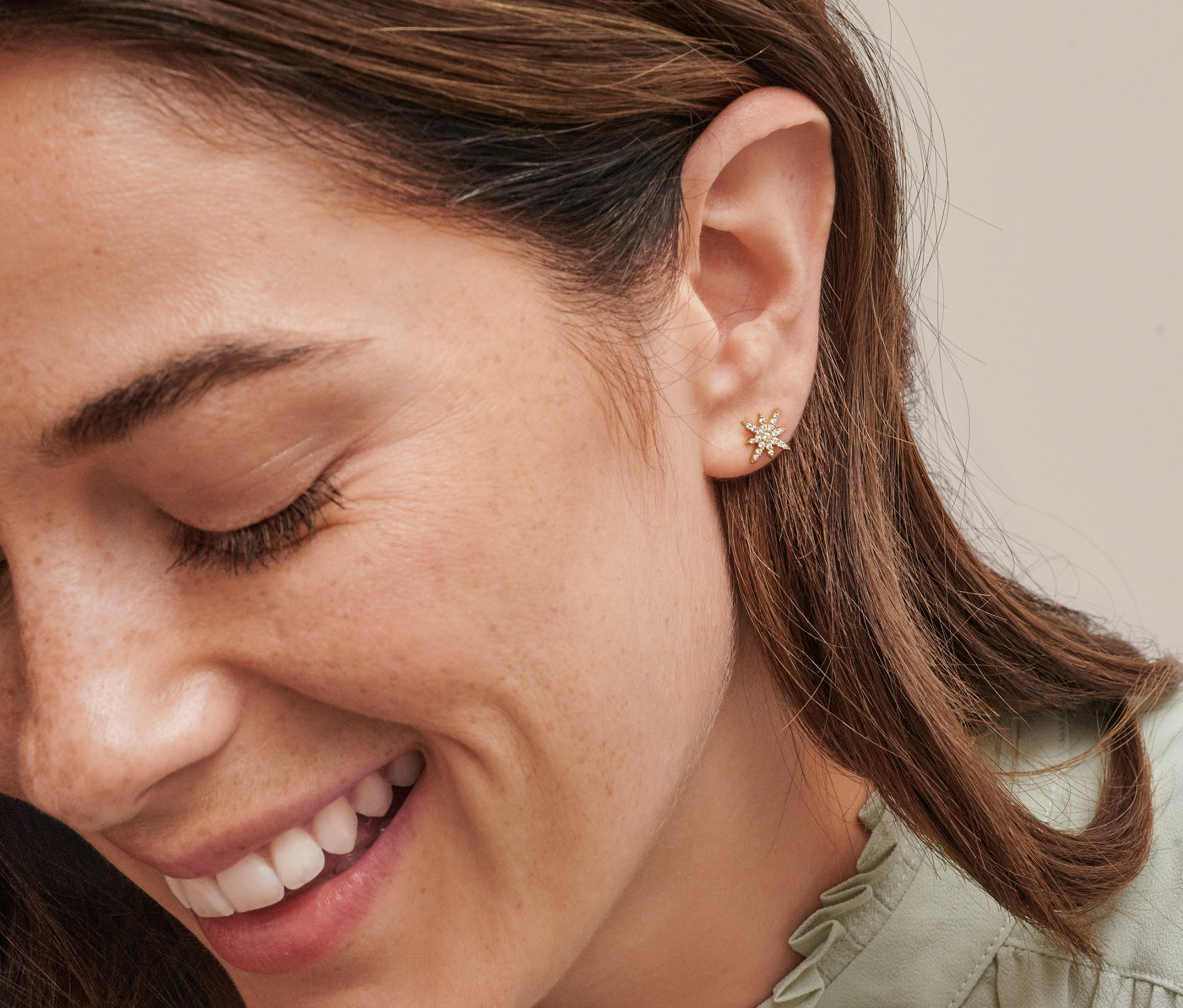 Detail obličeje usmívající se ženy s náušnicemi Zlaté náušnice Hvězda se zirkony.