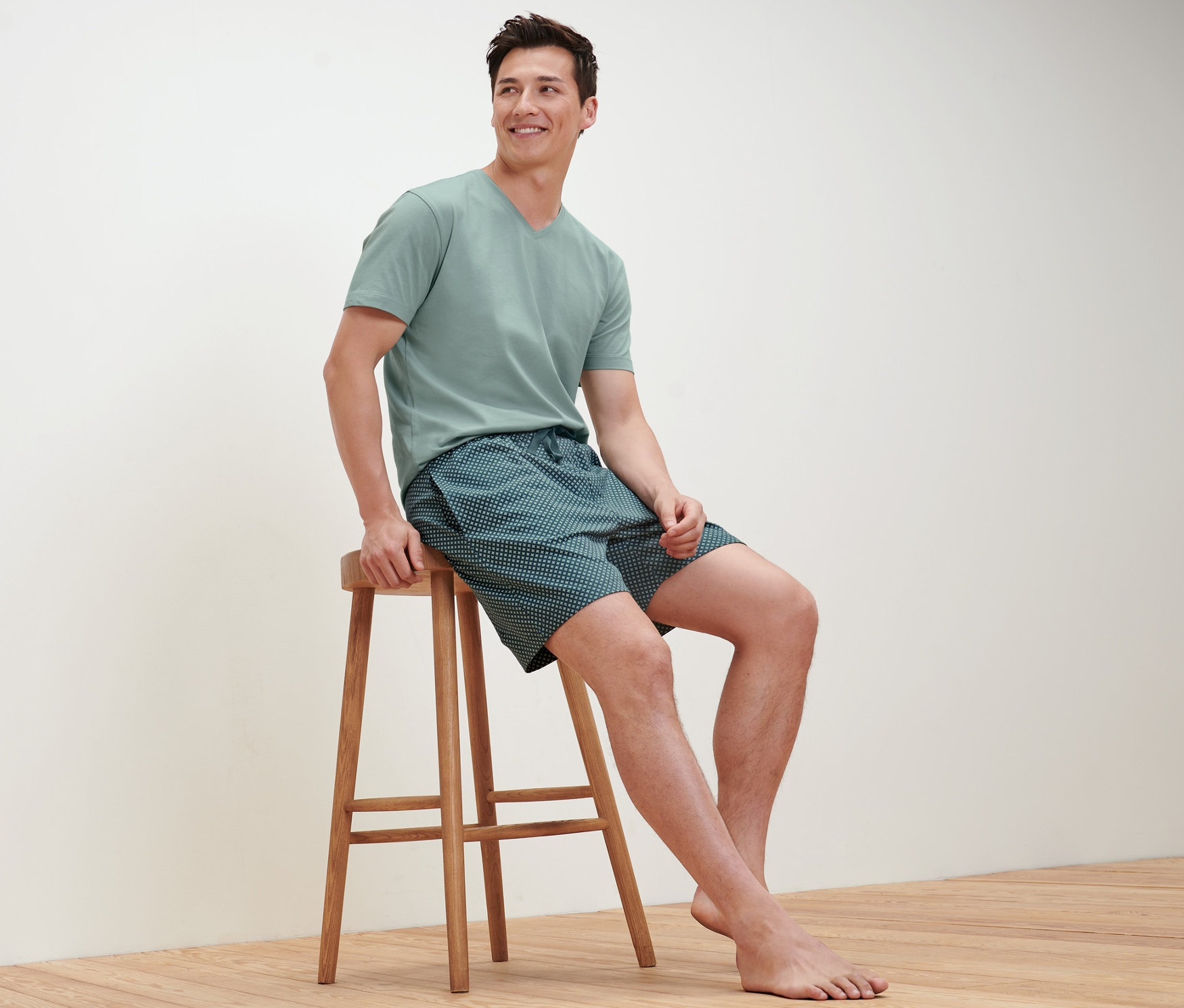 Muž sedí na stoličce a má na sobě krátké pyžamo.