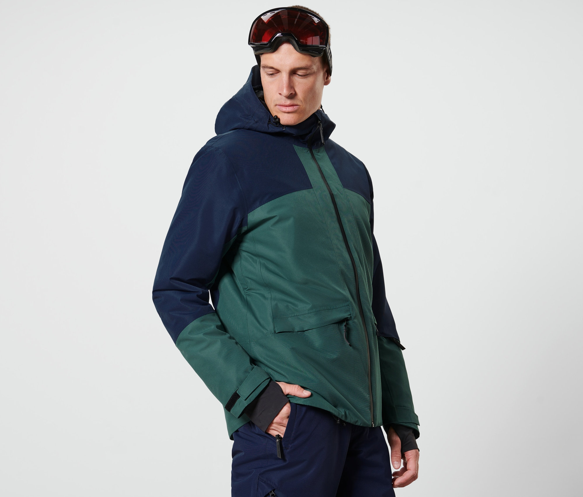 Muž má na sobě modrozelenou lyžařskou bundu.