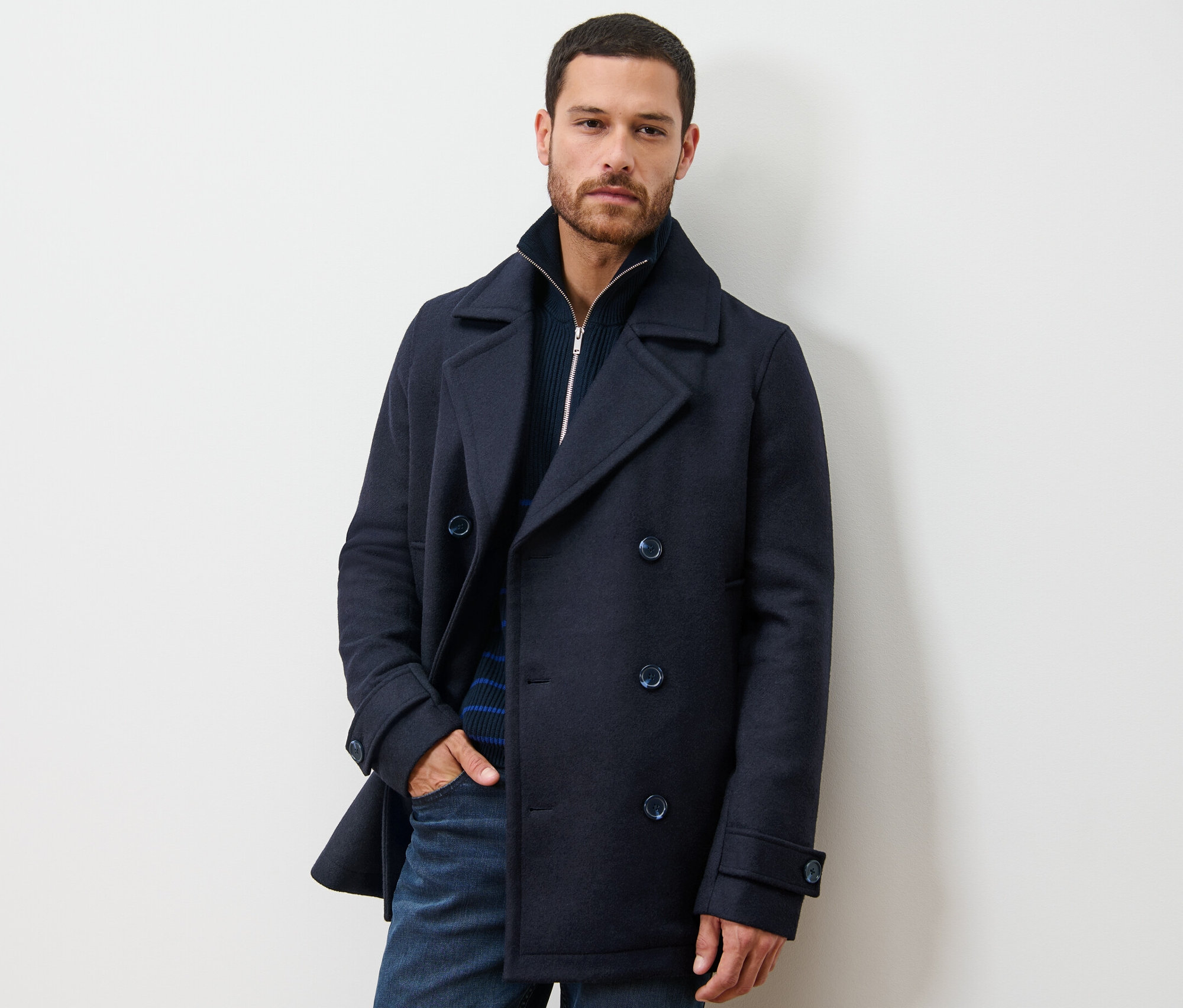 Muž pózuje v krátkém kabátu.