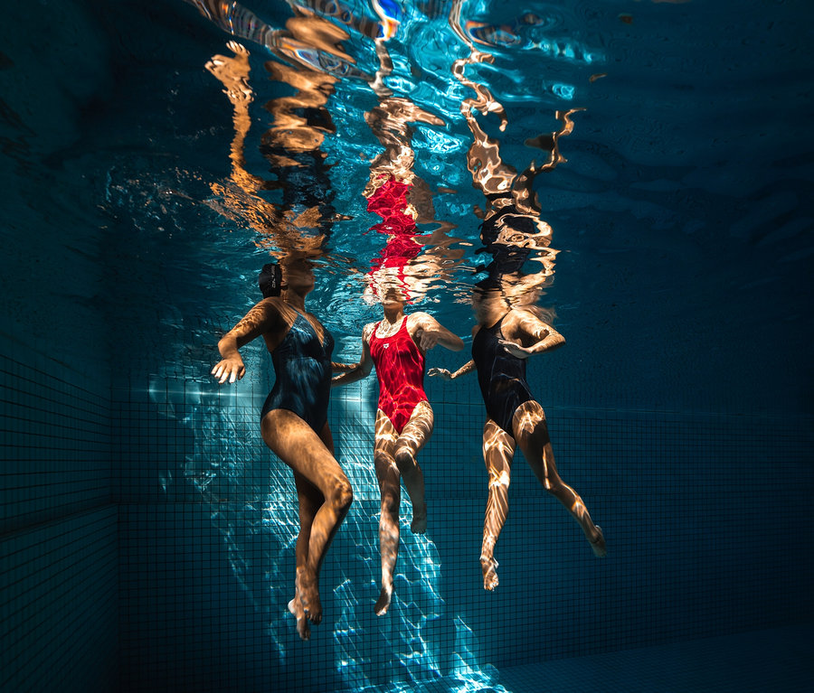 Tři ženy plavou pod vodou v bazénu. Jedna z nich má na sobě dámské plavky arena Shapewear Lara C Cup.