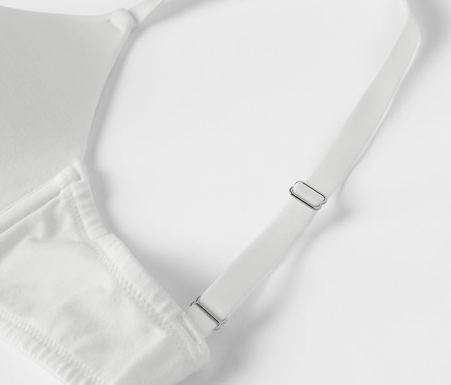 Detail bílé podprsenky s nastavitelnými ramínky.