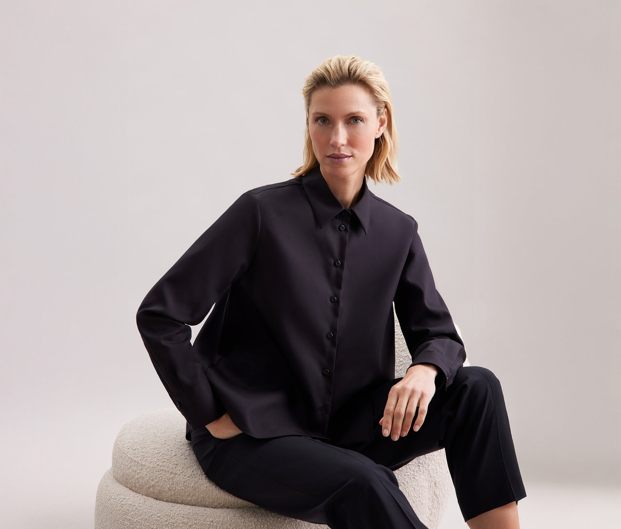 Žena sedí a má na sobě halenku Seidensticker Regular.