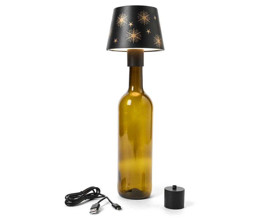 Stolní lampa vyrobená z olivově zelené skleněné láhve s černým stínidlem zdobeným zlatými hvězdami. USB kabel a černý spínač leží vedle lampy.