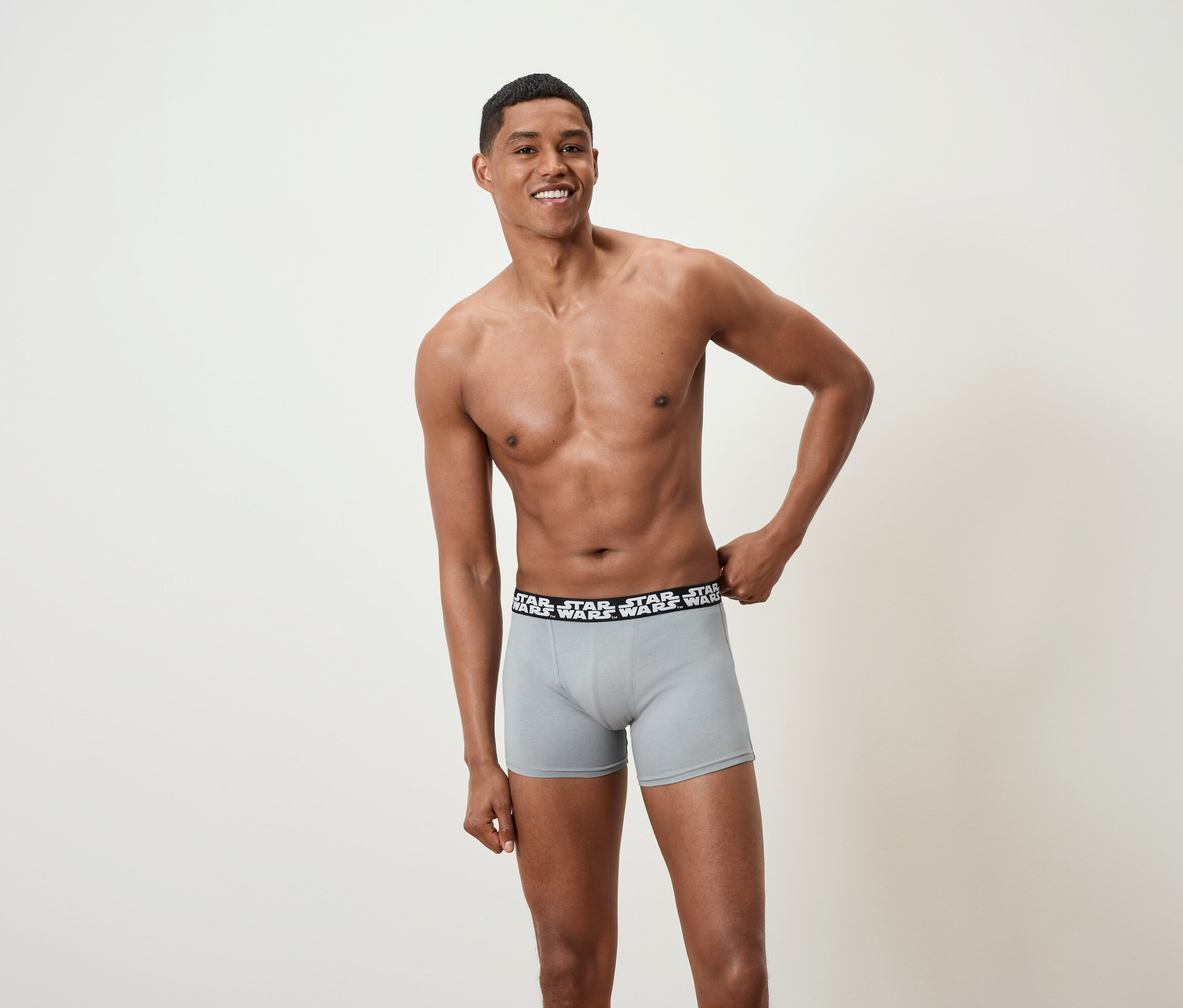 Usmívající se muž pózuje bez trička a má na sobě šedé boxerky se značkou Star Wars.