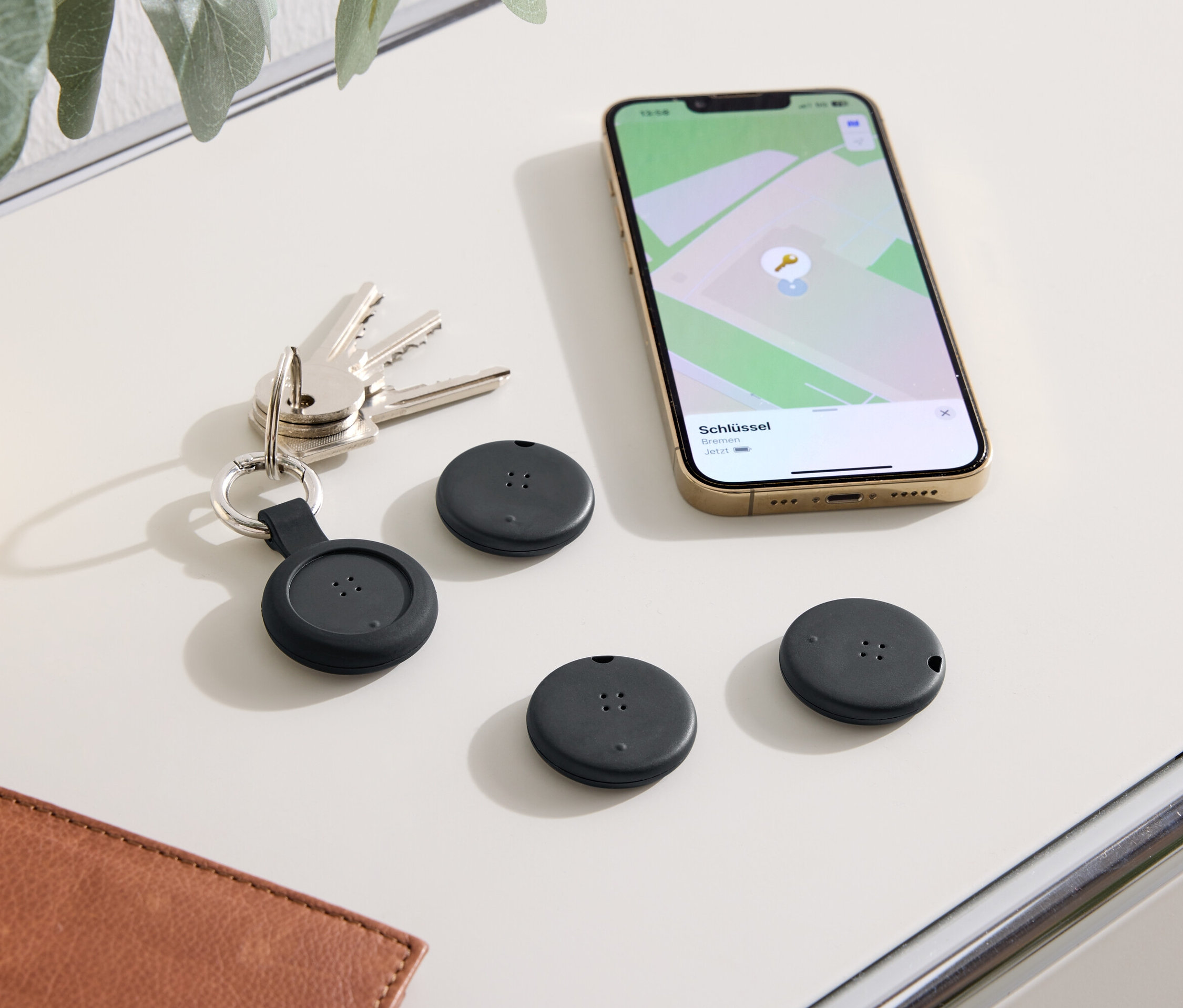 Na stole leží klíče, telefon s mapou a tři černé lokátory.