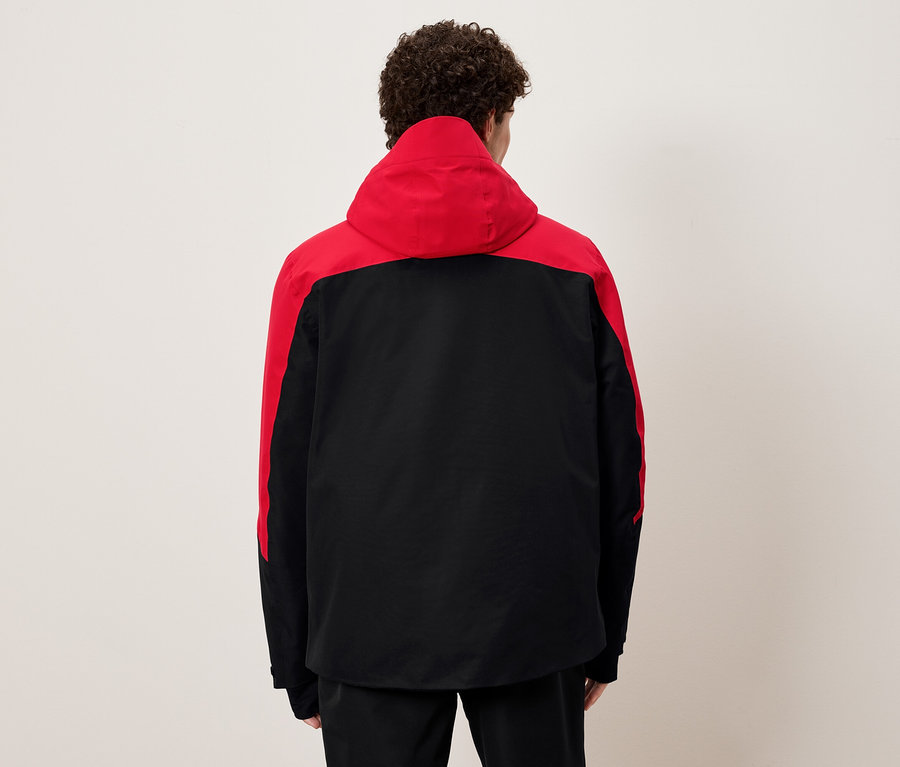 Muž zády k fotoaparátu má na sobě černou a červenou bundu s kapucí.