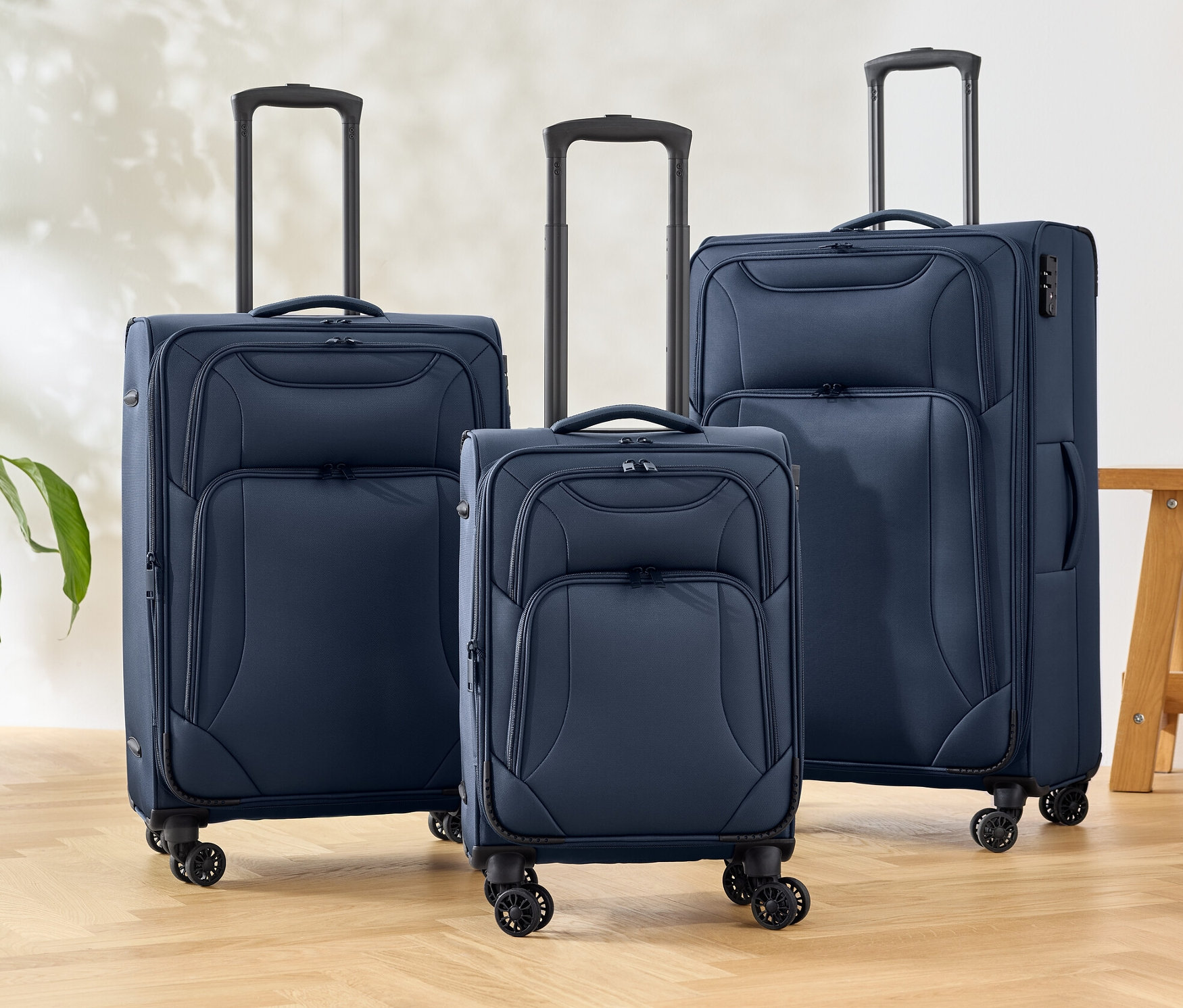 Tři textilní kufry v modré barvě stojí na podlaze.