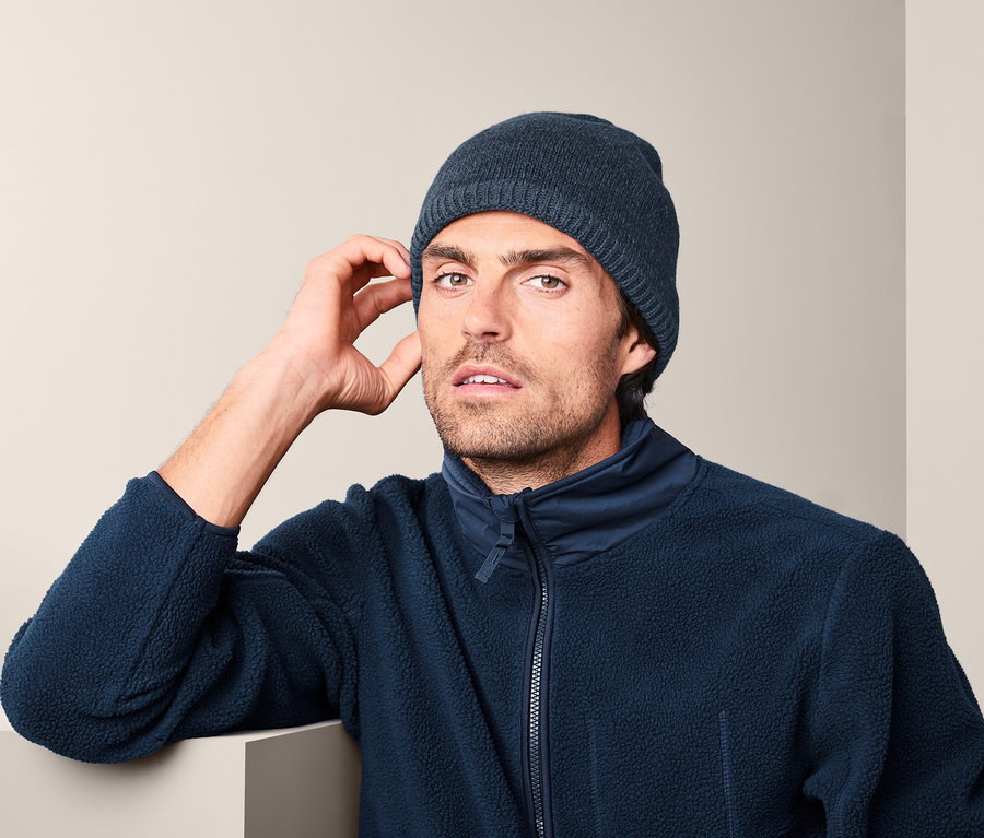 Muž s pletenou termo čepicí a fleecovou bundou.