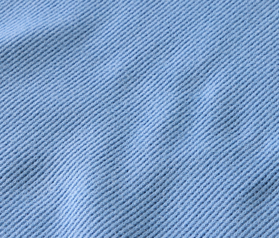 Detail světle modré látky s diagonálním žebrováním.
