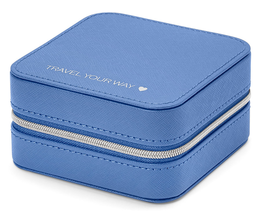 Detailní záběr na čtvercovou světle modrou šperkovnici se stříbrným zipem a nápisem „TRAVEL YOUR WAY“.