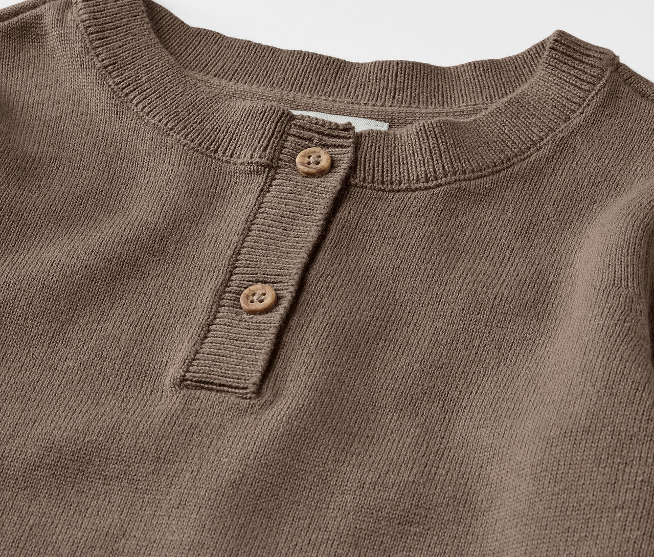 Detail hnědého dětského pleteného svetru henley s knoflíky.