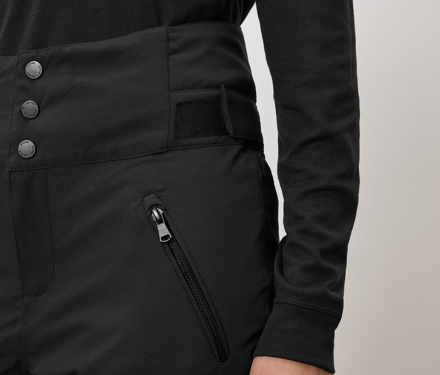 Černé kalhoty s vysokým pasem, zapínáním na tři knoflíky a kapsou na zip.