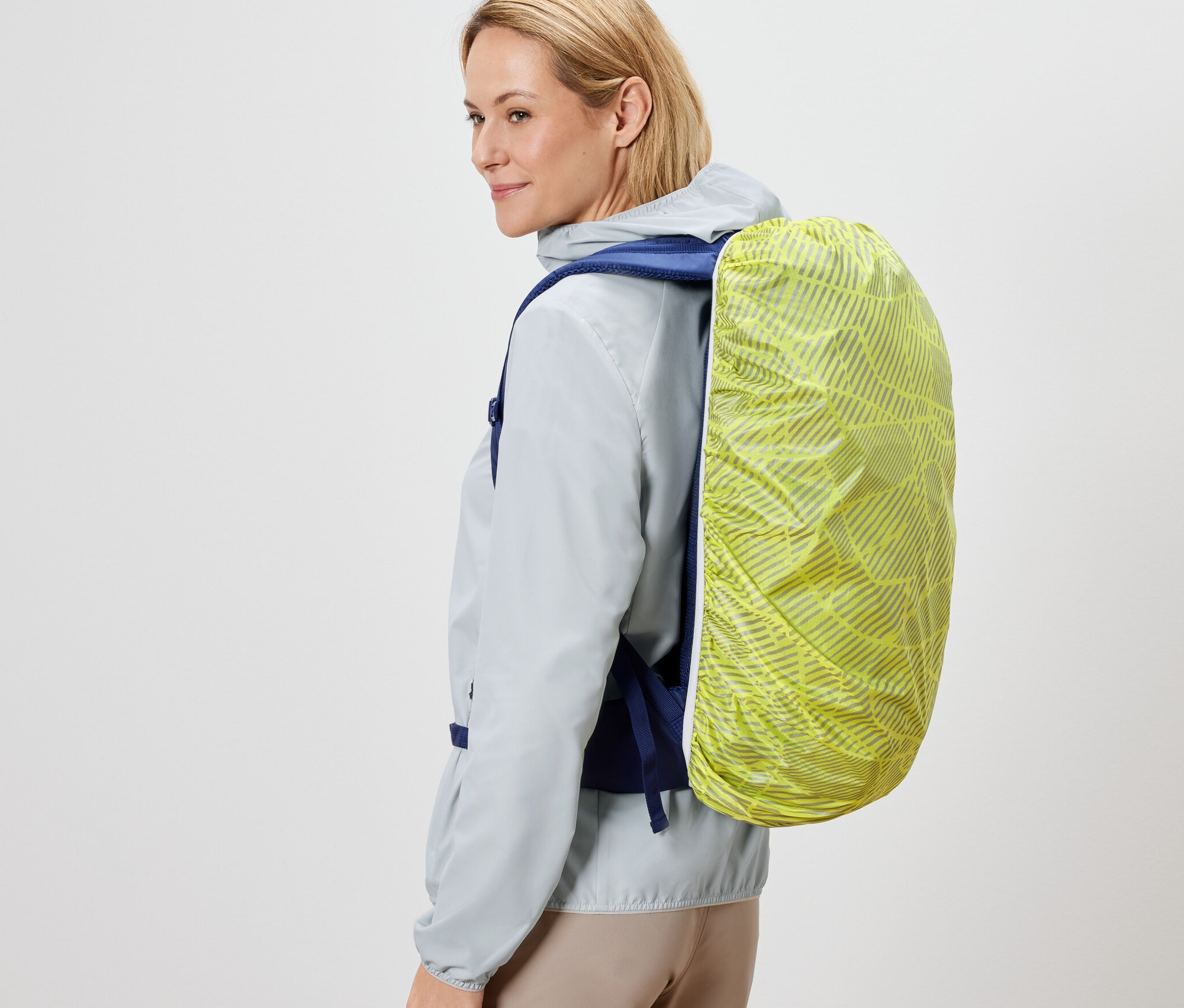 Žena má na zádech batoh s nepromokavým ochranným návlekem.