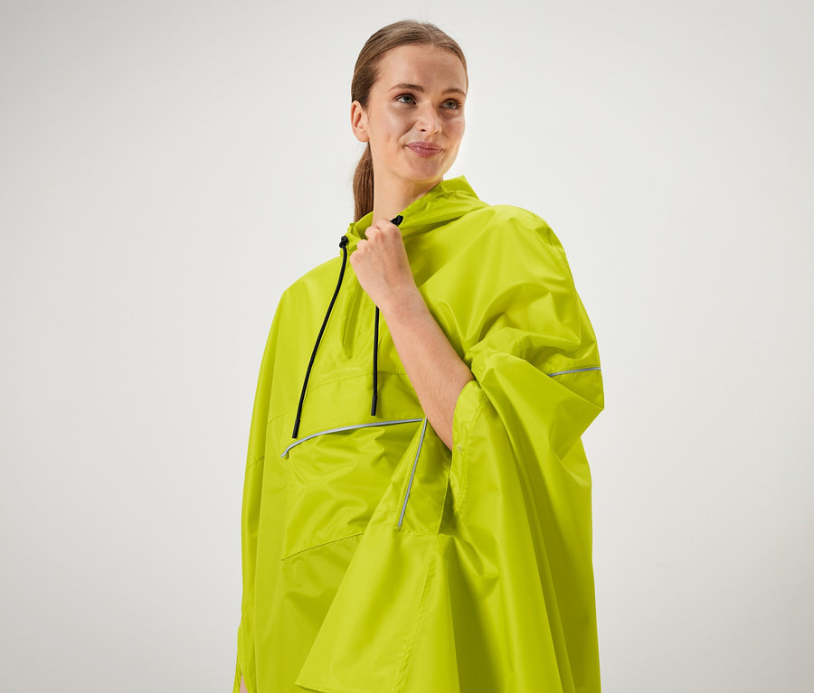 Žena sobě drží límec neonově zeleného ponča.