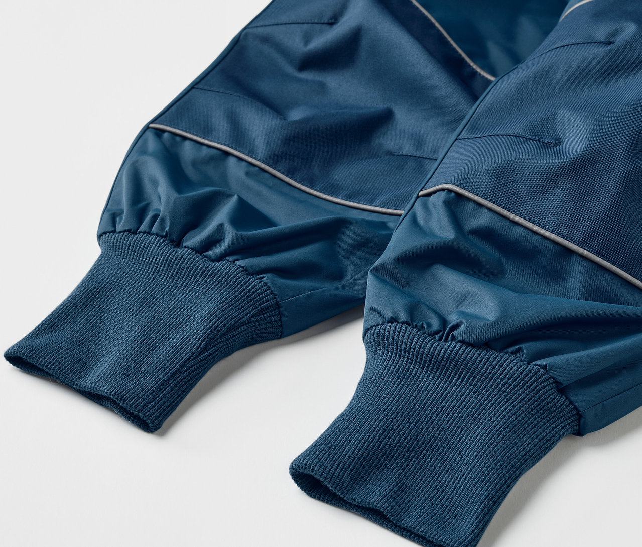 Detail dětských rostoucích kalhot do deště v modré barvě.