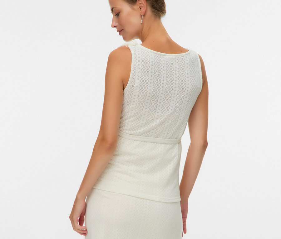 Žena zezadu v topu bez rukávů a sukni se vzorem.